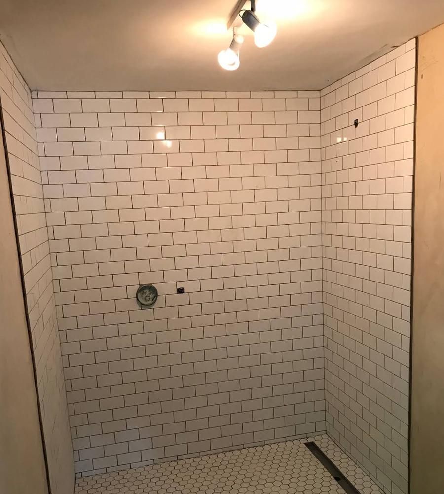 Tiled walk-in shower with white subway tiles and a linear floor drain